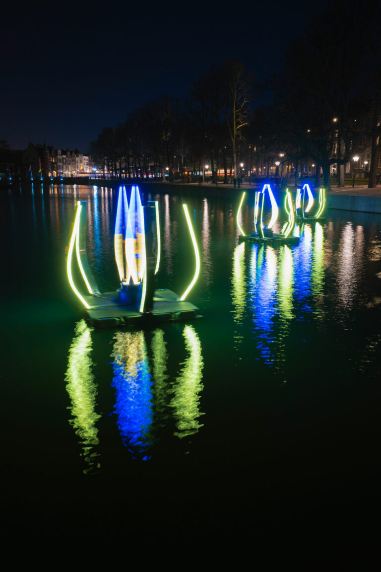 Colorful light installations on a canal at night.