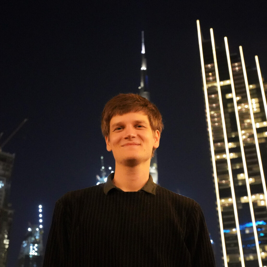 Person smiling with city lights at night.