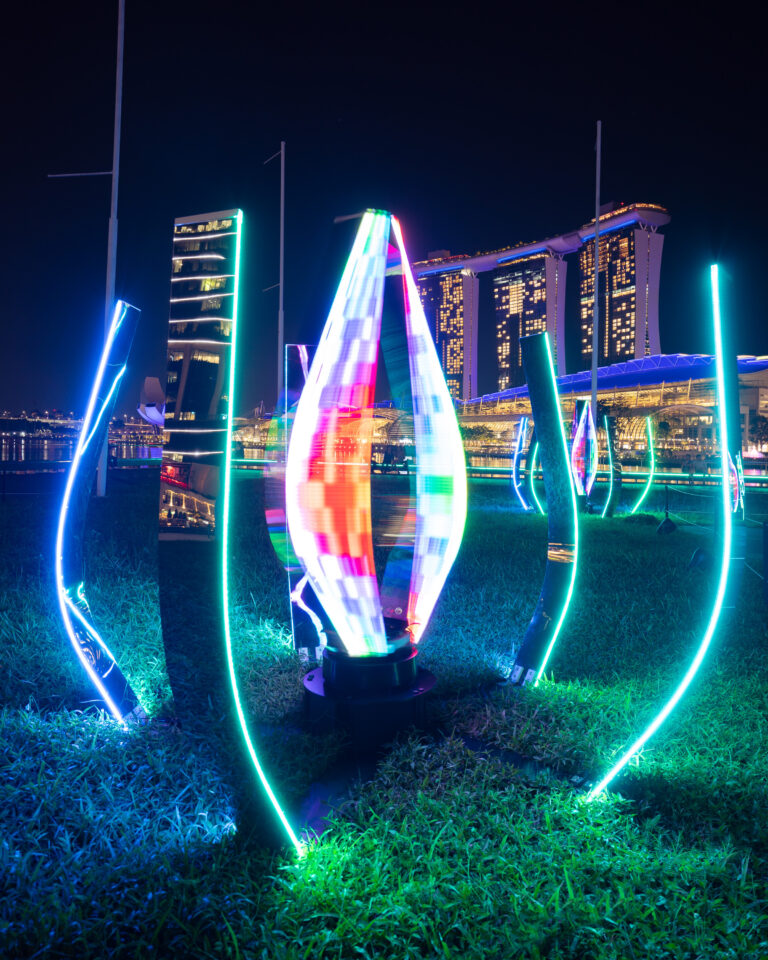 Colorful, illuminated sculptures at night, city skyline